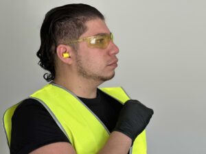 Tradie wearing Wave Bullet Earplugs and Hi-Vis Day Vest and Black Hog Nitrile Disposable Medical Grade Gloves or NexusFlex Nitrile Medical Grade Disposable Gloves from Your Safety Factory